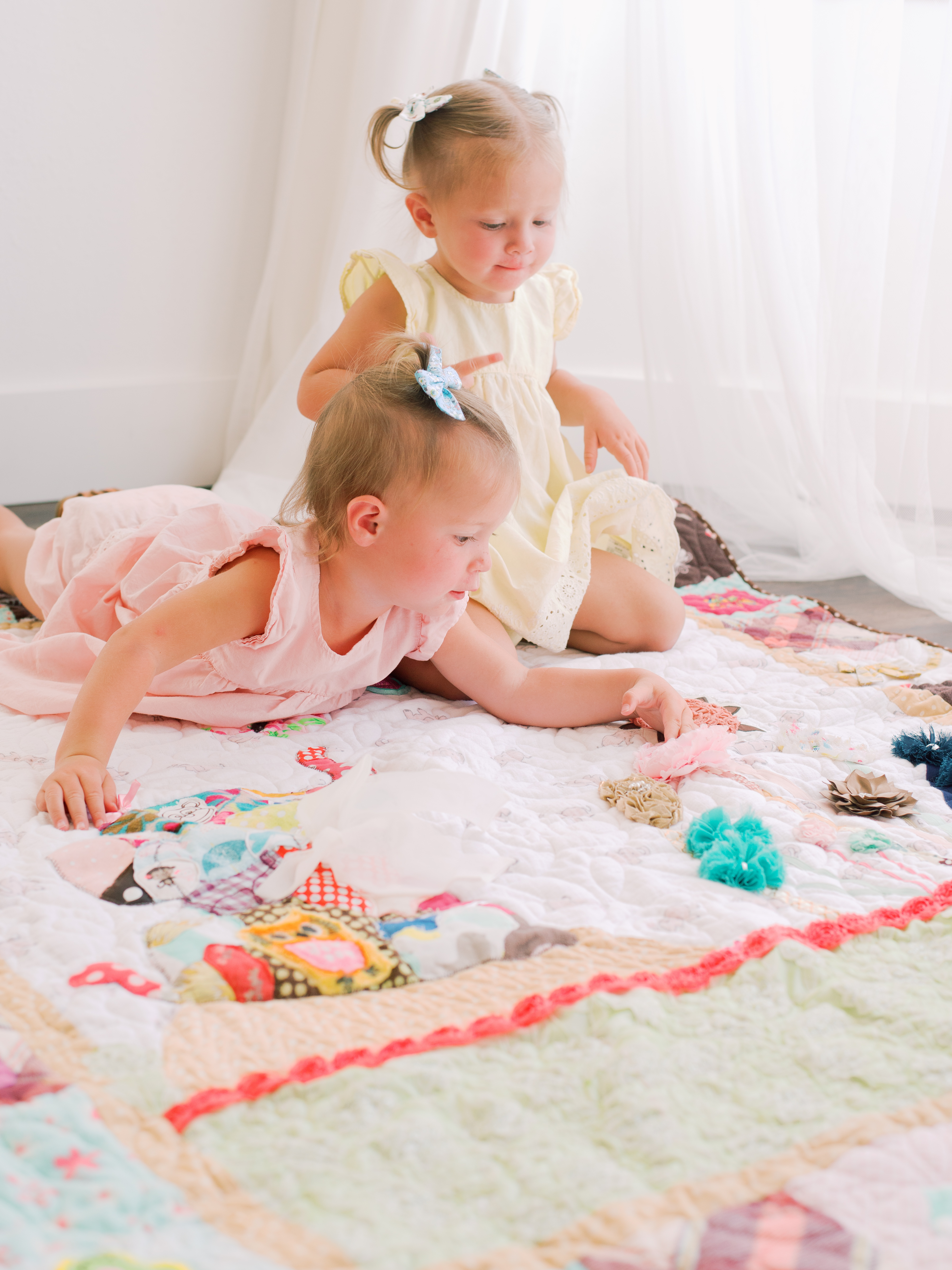 Image of two little girls laying on a quilt made from their little sister's clothes - also known as a memory quilt